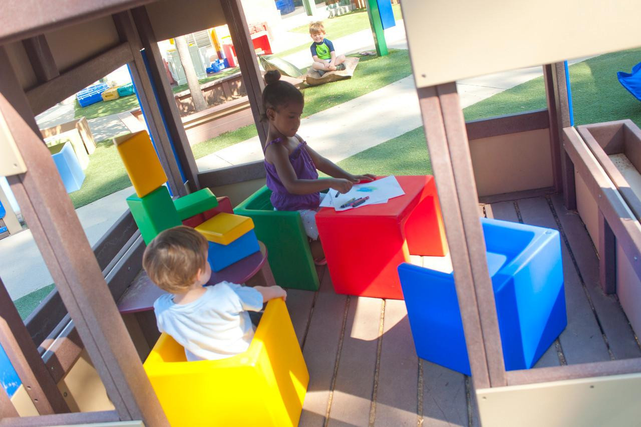 Children's Factory Children's Cube Chairs - 4 Primary Colors, colorful cube-shaped chairs in red, yellow, blue, and green used by children in an outdoor play area.